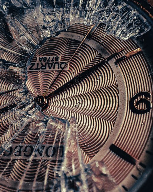 A detailed close-up of a cracked and shattered watch face revealing intricate designs.